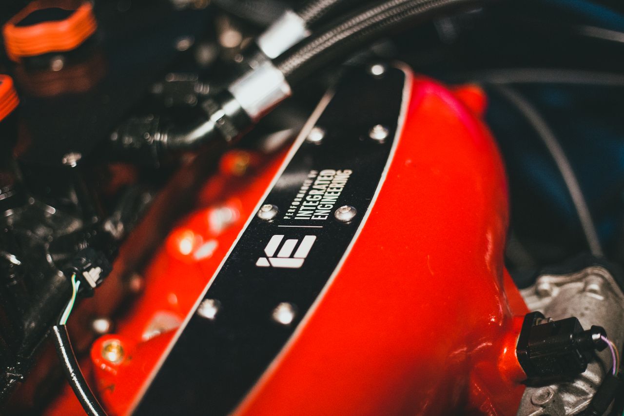 Detailed view of a red engine part with Integrated Engineering branding, showcasing automotive design.