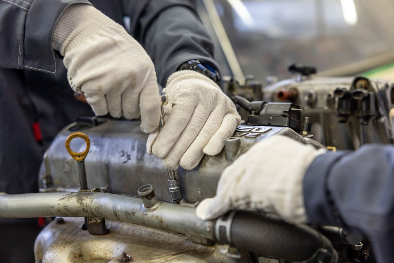 Close-up of mechanics hands repairing engine, showcasing teamwork and skill.