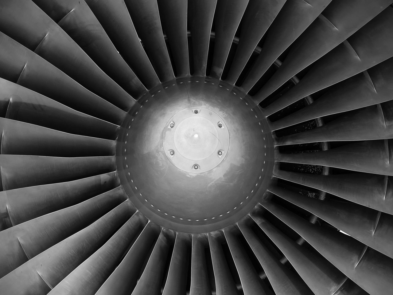 Monochromatic close-up of jet engine turbine blades showcasing intricate engineering design.